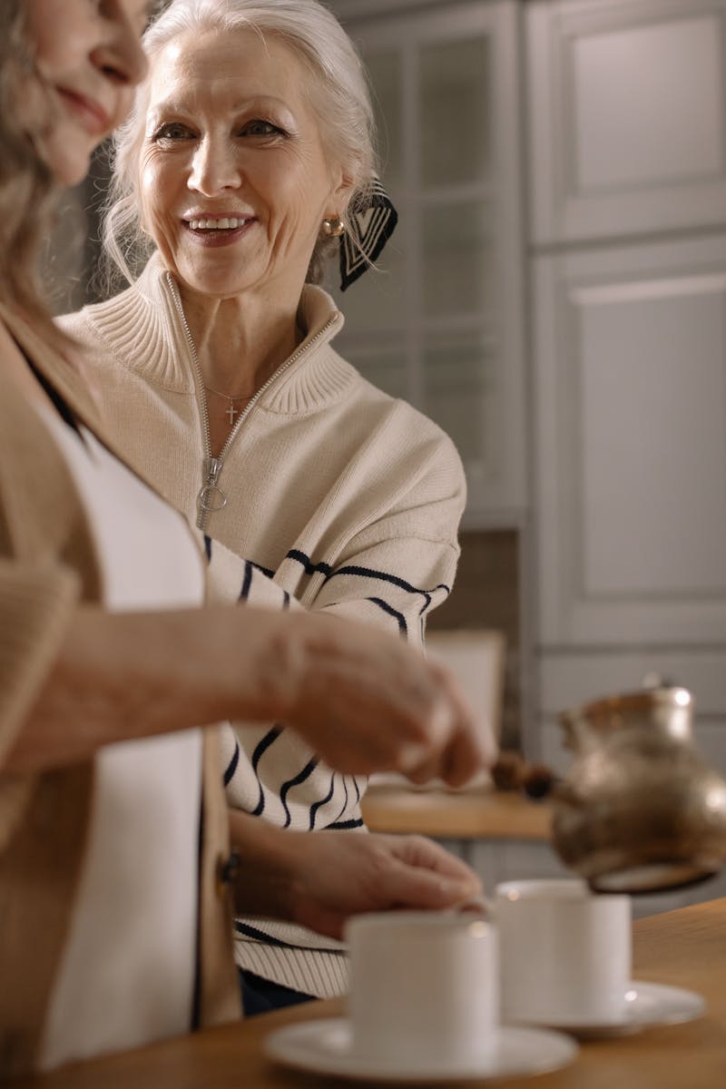 Two senior women smiling and enjoying coffee together indoors.