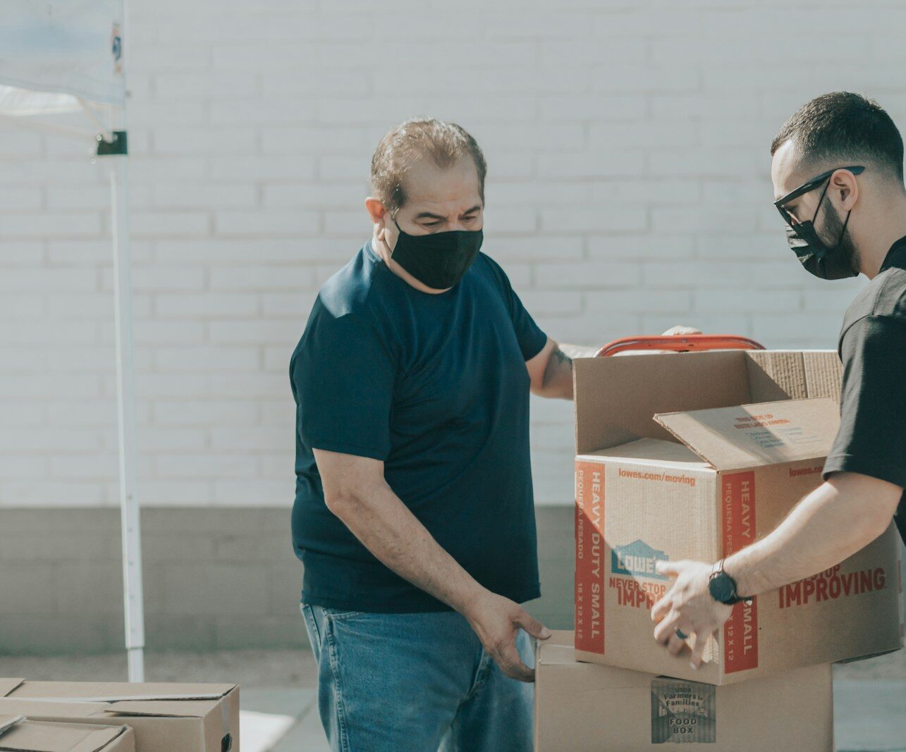 man in blue crew neck t-shirt standing beside brown cardboard boxes